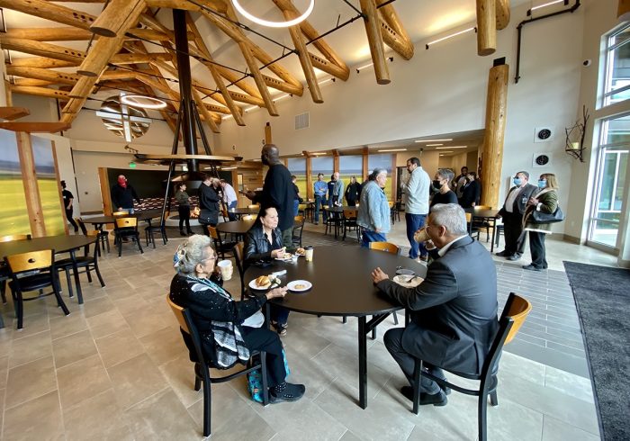 People are seated around tables in the dining room during the Grand Opening celebration with some people walking through the room